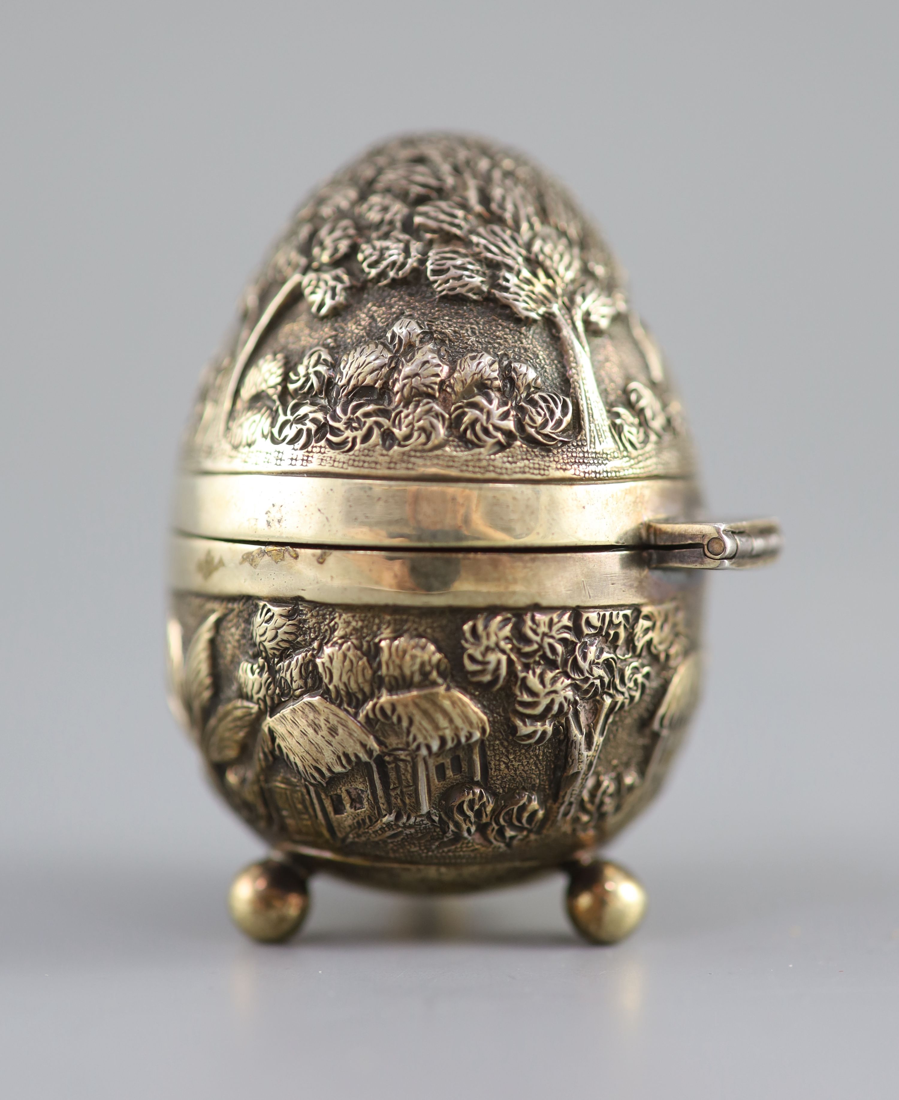 A graduated pair of Edwardian novelty silver gilt condiments, modelled as eggs, with bird's nest interior including two 'marbled' eggs